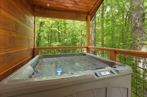 Un jacuzzi en una cabaña de madera con vista al bosque.