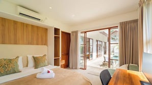 A hotel room with a bed, a wooden desk, a wardrobe, and a sliding glass door leading to an outdoor area. - Villa w/ Pool, Rice Field & Mountain Views (Pererenan)