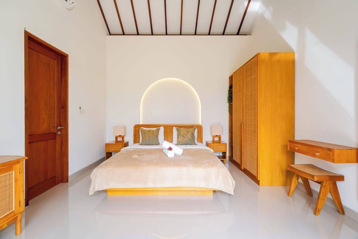 A bedroom with a large bed, bedside tables, a wardrobe, and a desk.