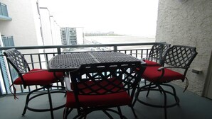 Un balcón con una mesa y sillas, vista a un edificio y barandilla.