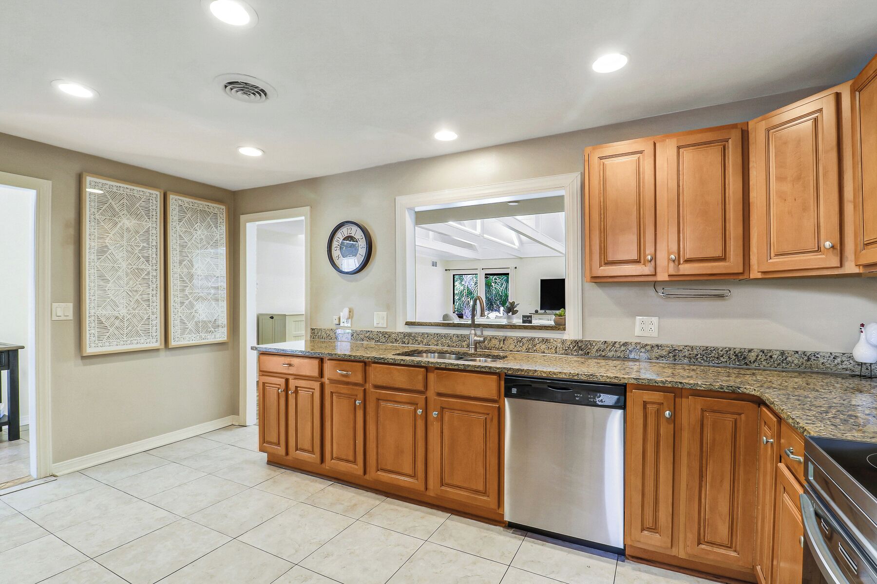 A kitchen with wooden cabinets, a granite countertop, a dishwasher, and a built-in oven.