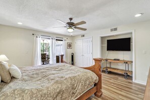 A bedroom with a bed, a ceiling fan, a television, and a desk with a chair. - Sunset Rentals | Queens Grant 671 | Dog Friendly (Hilton Head Island)