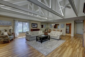 Ein geräumiges Wohnzimmer mit Holzdielen, zwei Sofas, einem Couchtisch und einem Deckenventilator.