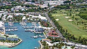 A marina with boats, a golf course, and a resort area with buildings and a beach.