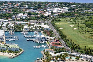 A marina with boats, a golf course, and a resort area with buildings and a beach.