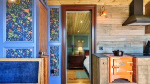 Een kamer met een bed, een dressoir, een houten plafond en een fornuis.