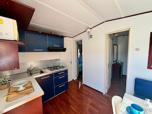 A compact kitchen with a gas stove, blue cabinets, and a wooden countertop.