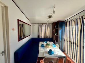 A compact room with a dining table, blue sofa, and a mirror.