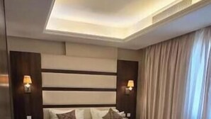 Une chambre d’hôtel avec un grand lit, des tables de chevet, une chaise, un bureau et une moquette à motifs.