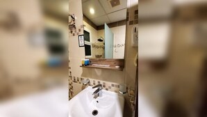 Une salle de bain avec un lavabo blanc, un miroir et une douche.