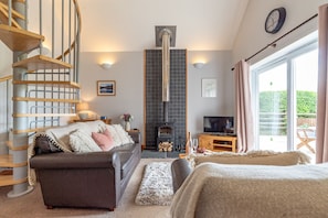A modern living room with a fireplace, a sofa, a TV, and a spiral staircase.