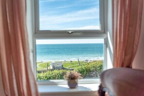 Ein Fenster mit Blick auf den Ozean und eine Rasenfläche mit einem Gebäude.