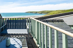 Ein Balkon mit Blick auf das Meer, ein Tisch mit einer Laterne und ein Stuhl.