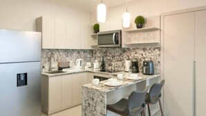 Een moderne keuken met een marmeren aanrecht, roestvrijstalen apparatuur en een centraal eiland met barstoelen.