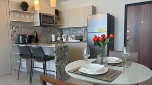 Een moderne keuken met een eetgedeelte, voorzien van een koelkast, magnetron en diverse apparaten.