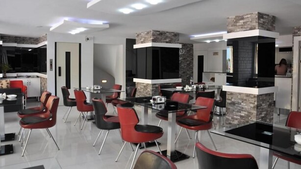 Un espace repas moderne avec des chaises rouges, une table en verre et une cuisine en arrière-plan.