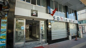 Un bâtiment sur lequel on peut lire l’inscription « Sahin Otel » et au-dessus de l’entrée flotte un drapeau rouge.