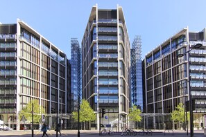 Ein modernes Gebäude mit einem zentralen Turm und symmetrischen Flügeln, das große Fenster und eine Glasfassade aufweist.