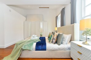 Ein modernes Schlafzimmer mit Bett, Nachttisch, Lampe und Kleiderschrank.