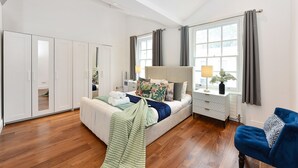 A bedroom with a bed, bedside table, lamp, curtains, and a wardrobe. - Knightsbridge Beauchamp Exclusive II - 46bp (London)