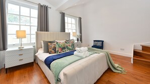 A bedroom with a bed, nightstand, lamp, and a view of the outside through large windows. - Knightsbridge Beauchamp Exclusive II - 46bp (London)