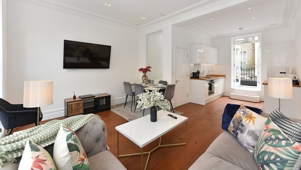 A modern living room with a flat-screen TV, a dining area, and a kitchen. - Knightsbridge Beauchamp Exclusive II - 46bp (London)