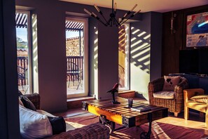 A living room with a sofa, a wicker chair, a coffee table, and a map on the wall.