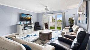 Sala de estar com televisão, sofá, mesa de centro e ventoinha no teto.
