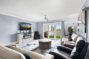 Ein Wohnzimmer mit Fernseher, Sofa, Couchtisch und Deckenventilator.