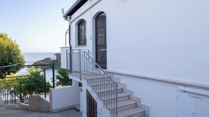 A white building with a staircase leading to a balcony overlooking the sea. - Lilium Gaeta Apartment by Mamo Florence (Gaeta)