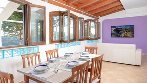 A dining area with a table set for four, wooden chairs, and a white sofa in the background. - Lilium Gaeta Apartment by Mamo Florence (Gaeta)