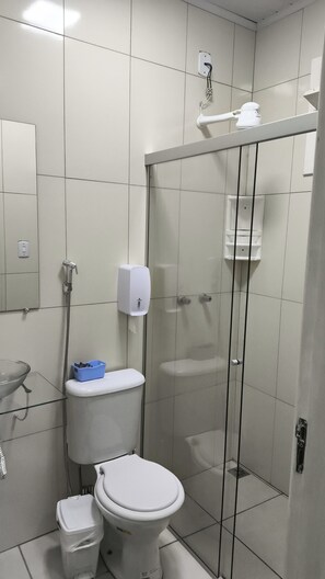 Kylpyhuone, jossa on wc, lasinen suihkuseinä, nestesaippua-annostelija ja peili.