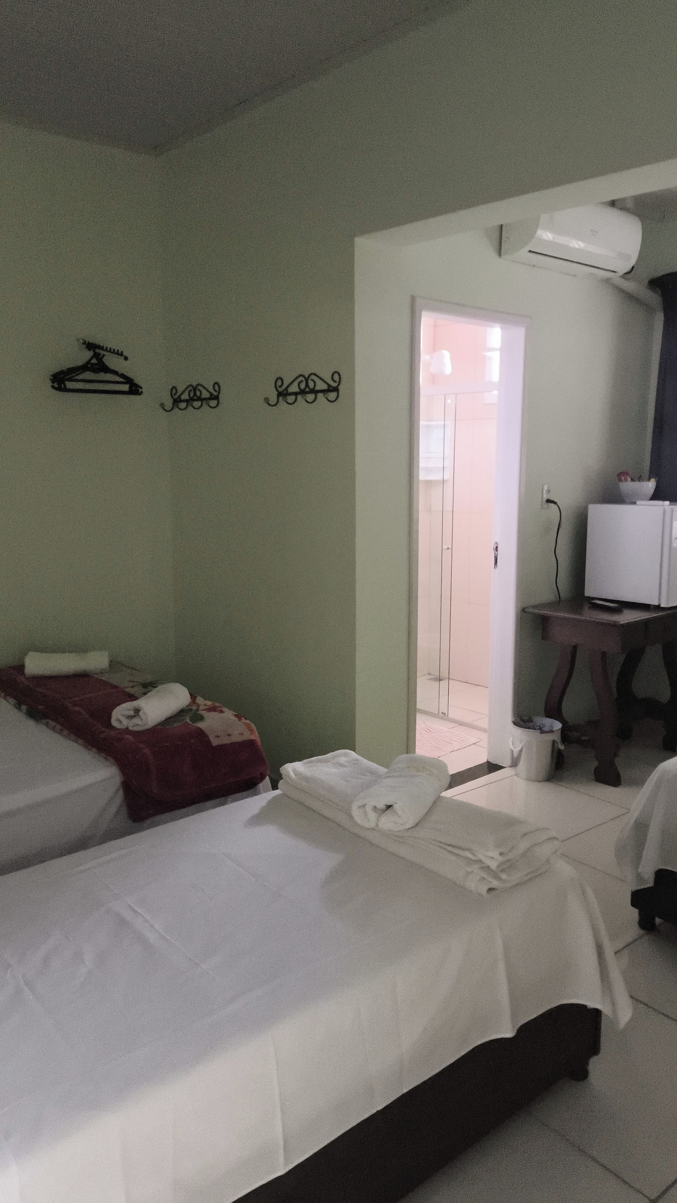 Habitación de hotel con dos camas, televisión y baño visible a través de una puerta abierta.