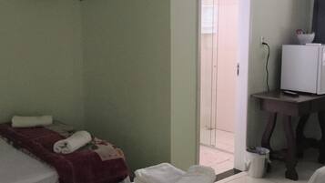 Habitación de hotel con dos camas, televisión y baño visible a través de una puerta abierta.