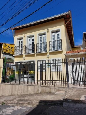 A two-story building with a gated entrance, balconies, and a signboard.