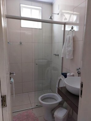 Une salle de bain avec une douche à parois de verre, des toilettes, un lavabo et une serviette accrochée au mur.
