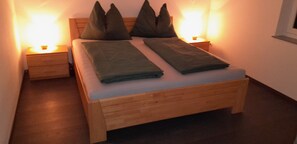 Una cama bien hecha con almohadas, un cabecero de madera y mesitas de noche con lámparas.