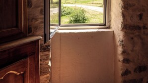 A room with a wooden ceiling, a stone wall, and a window with a view of a green landscape. - Ardèche estate from 1748 - Private heated pool - 16 travelers (Saint-Barthélemy-Grozon)