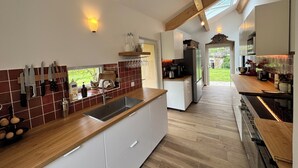 A modern kitchen with a wooden countertop, white cabinets, and a large island. There are various kitchen appliances and utensils visible. - Ardèche estate from 1748 - Private heated pool - 16 travelers (Saint-Barthélemy-Grozon)