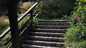 A wooden staircase with stone steps leading up to a wooden deck.