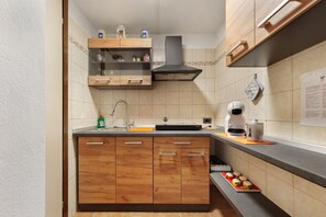 Eine Küche mit Holzausstattung, einer Edelstahlspüle und einer Kaffeemaschine.