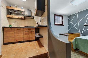 Une cuisine de taille réduite, avec des meubles de rangement en bois, un évier et une fenêtre.