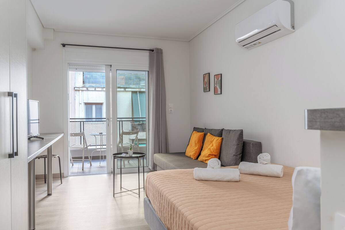 Una habitación de hotel con cama, escritorio, silla, una mesita y un balcón con silla y mesa.