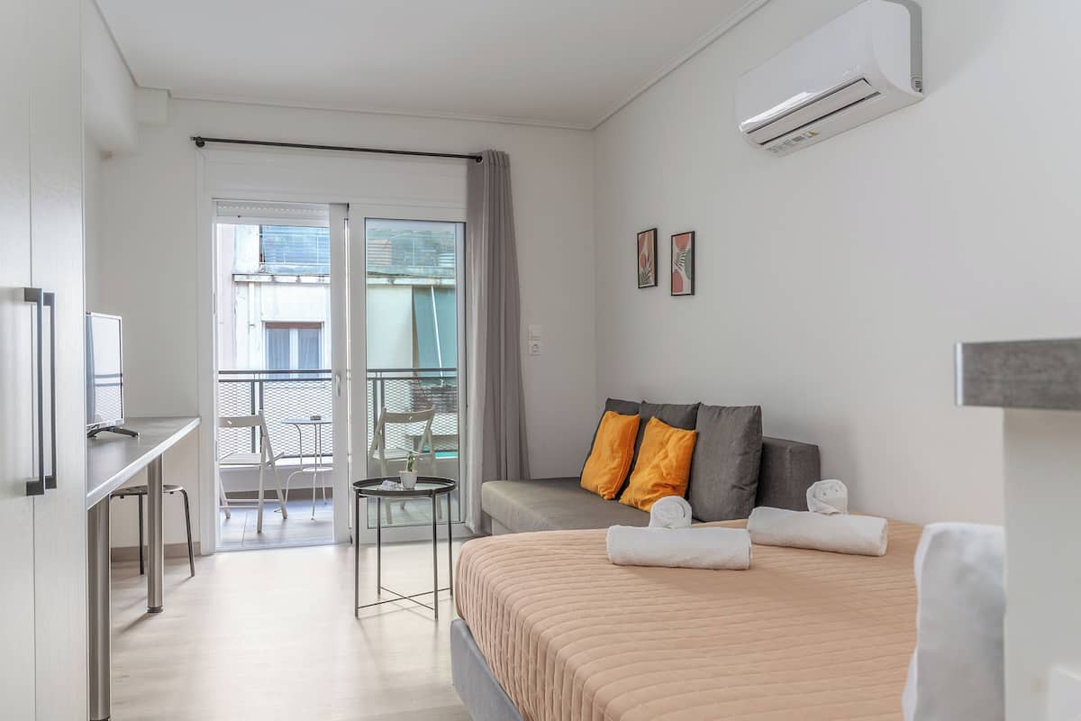 Une chambre dâhĂŽtel comprenant un lit, un bureau, une chaise, une petite table et un balcon avec une chaise et une table.