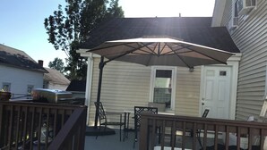 Un patio couvert équipé d’un barbecue, de meubles d’extérieur et d’une porte donnant accès à la maison.