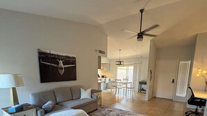 Ein geräumiges Wohnzimmer mit Sofa, Couchtisch, Teppich, Essbereich mit Stühlen und einer Küche im Hintergrund.
