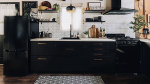 A modern kitchen with black appliances, white tiles, and wooden accents. - Firefly Cabin (Big Bear Lake)
