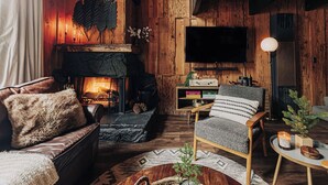A cozy living room with a fireplace, a television, and a comfortable seating area. - Firefly Cabin (Big Bear Lake)