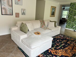 Ein Wohnzimmer mit einem weißen Sofa, einem gemusterten Teppich und Wandbildern.