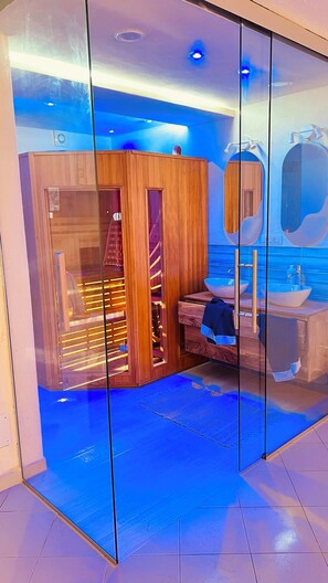 Een moderne badkamer met een houten wastafelmeubel, een grote spiegel en een blauwe betegelde vloer.